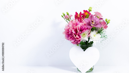 Beautiful bouquet of natural fresh flowers in glass jar with paper heart.
