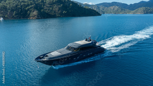 Foto Sleek Yacht Cruising: A luxurious motor yacht elegantly cuts through the serene, crystal-clear blue waters, leaving a trail of shimmering wakes