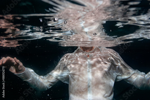 фотографія Artistic underwater portrait of person in white shirt floating beneath water surface