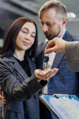 Фотография Realtor handing over house keys to a couple in a modern office setting, with a c
