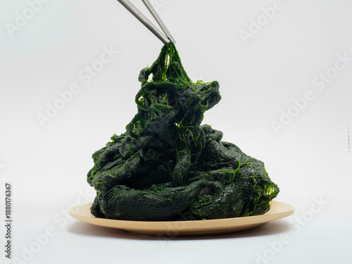 Image of dark green seaweed in a round shape on a white plate, showing a fine, delicate thread-like texture. Korean food ingredients used.