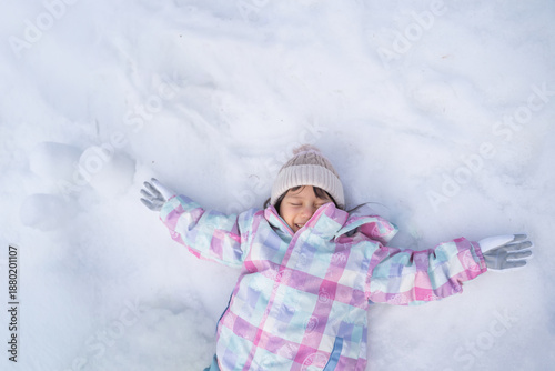 Fotografía 雪の上で両手を広げて寝る子供