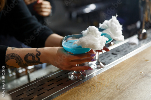 Bright blue cocktails topped with cotton candy are served at a trendy bar during the evening hours