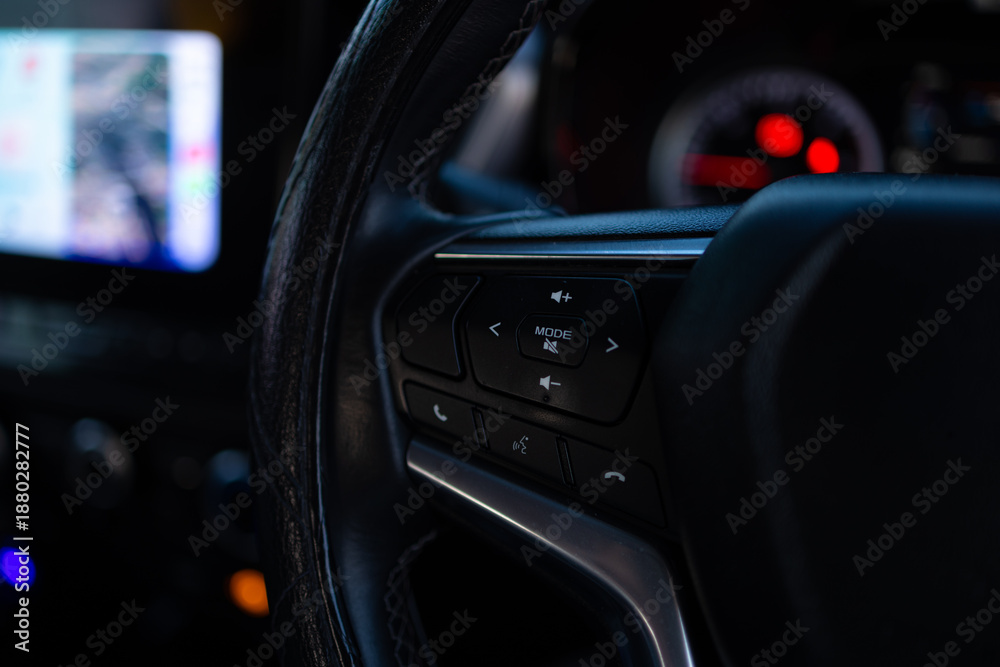 Naklejka premium Close-up of Multifunction Steering Wheel Controls in a Modern Car,A detailed close-up shot of the steering wheel control buttons in a modern vehicle, featuring audio volume, mode selection, 