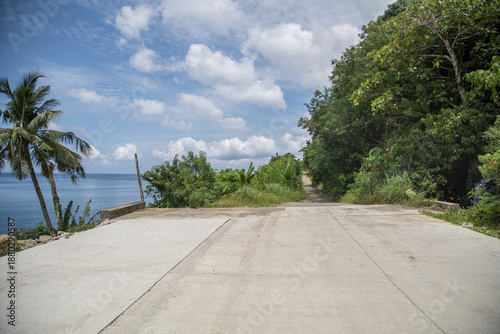 wide concrete road along the tropical coastline end in a rough road