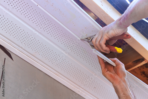 Billede på lærred Person installs ceiling trim using tools in room