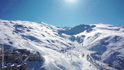 Aerial 4K video from a drone to Sierra Nevada ski resort on a sunny winter day in the mountains, Spain. Sierra Nevada is the largest mountain range near the city of Granada in Spain with snow. Sierra 