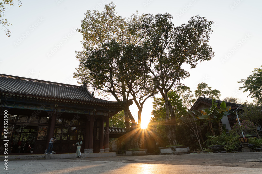 Fototapeta premium Sunset Behind a Tree in a Traditional Courtyard, West Lake in Huizhou, Guangdong Province, Asia China, is a tourist attraction featuring ancient architecture