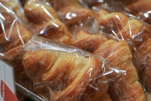 Fresh, individually wrapped croissants on a store counter. Appetizing baked goods. Close-up.