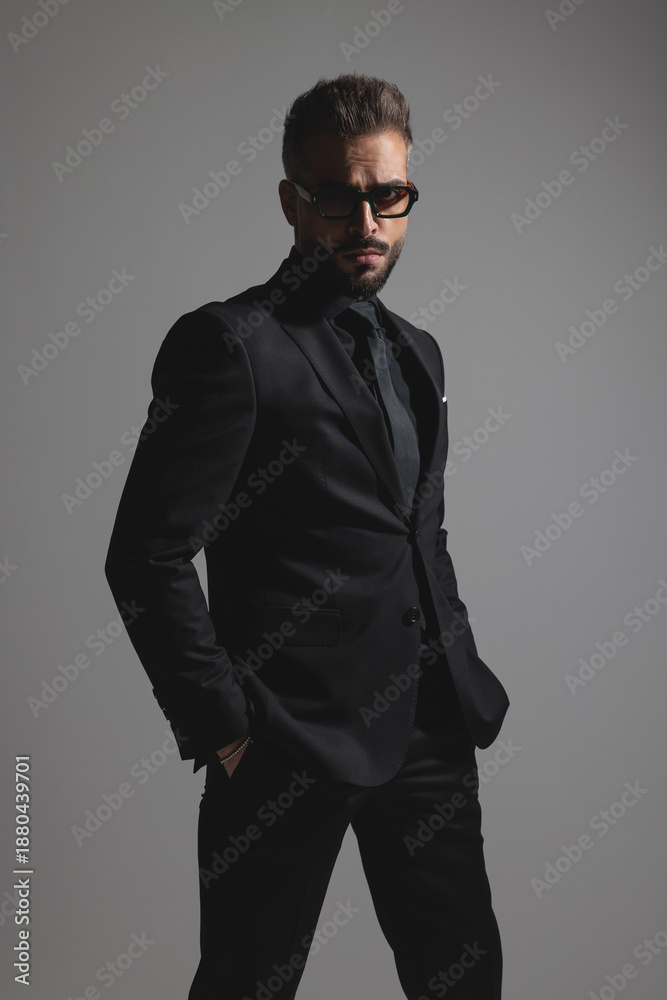 Fototapeta premium Serious fashion man in suit standing with hands in pockets