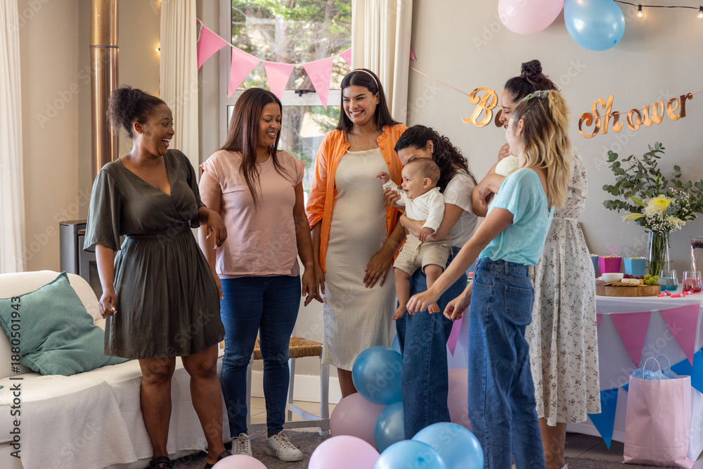 Obraz premium Diverse family with friends standing around pregnant woman in living room with baby shower banner