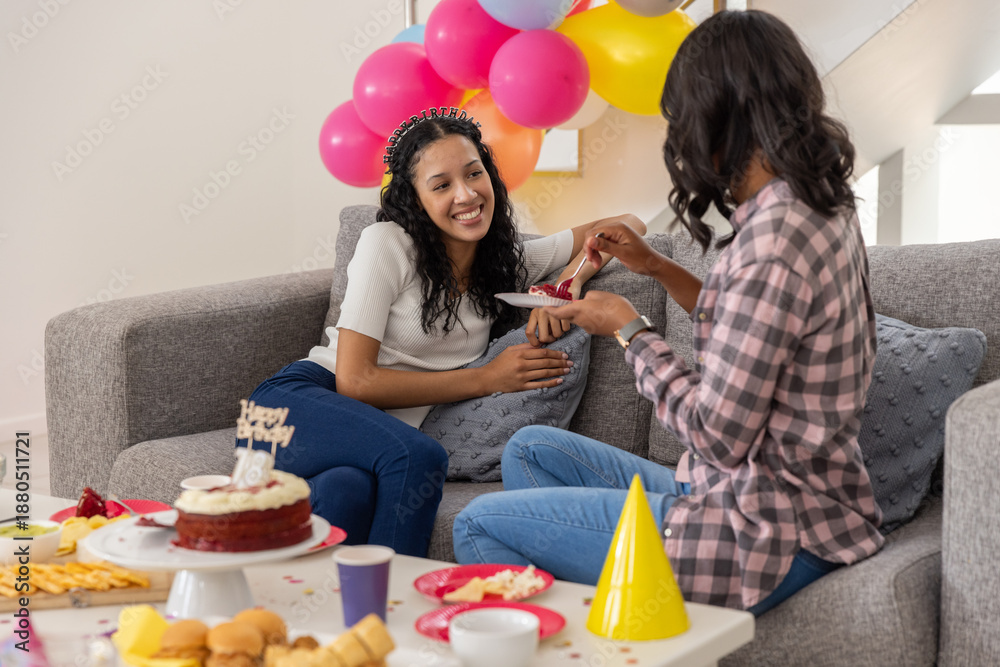 Obraz premium Diverse mom and teenage daughter sitting on couch for birthday sharing velvet cake slice