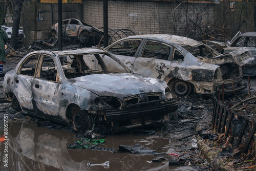 A row of burned-out civilian cars in an area flooded by shelling. Extensive destruction of vehicles and the urban environment in the war zone. A dramatic view of the aftermath of war.