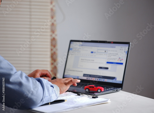 Buying and selling cars online. A man wants to buy a used car. He's browsing through numerous used car listings online on his laptop to compare prices. Many automobiles with picture detail.
