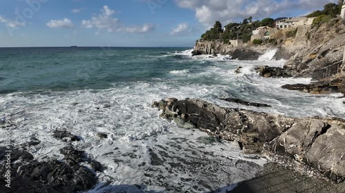 Powerful ocean waves crashing on shore rocks during cloudy day in Bogliasco Italy
