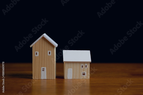 Photos Two wooden house models on table with dark background and copy space