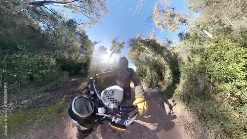 Chico con casco negro en moto clasica viajando por carretera y terreno boscoso en dia soleado ,toma grabada en 4k