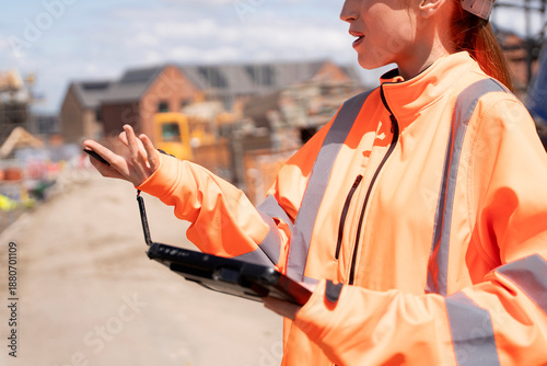 Принти на полотні Portrait of smiling young woman builder site engineer in bright safety gear usin
