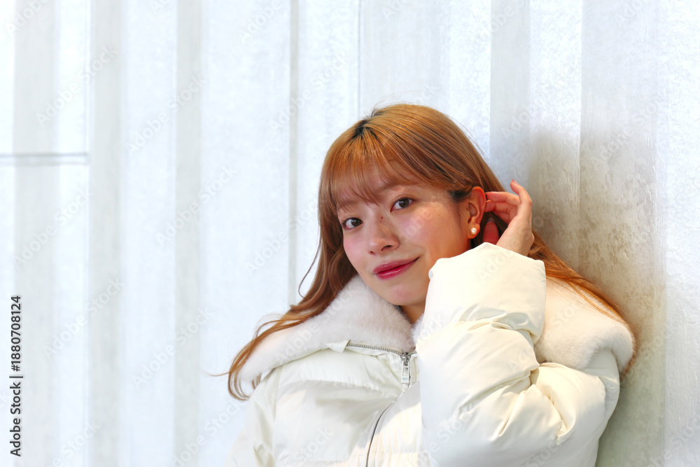 Naklejka premium 耳に手を当てて微笑む明るい表情の若いアジア人女性のポートレート 