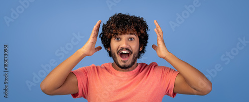 Canvas Print A person with curly hair stands against a blue background displaying a surprised expression