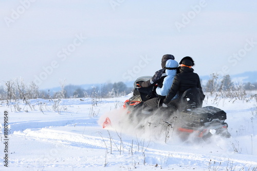A family snowmobile ride through snow-covered meadows on a sunny winter day