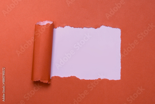 Torn hole in red paper with white background inside and scroll, ripped paper frame with copy space for text, creative template for message, breakthrough and discovery concept