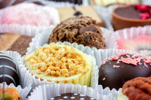 Luxury individual chocolates in paper cases close up. Amazing toppings on white and dark chocolate sweet treats.