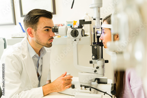 Tableau sur toile Hispanic ophthalmologist examining patient's vision with a slit lamp during a co