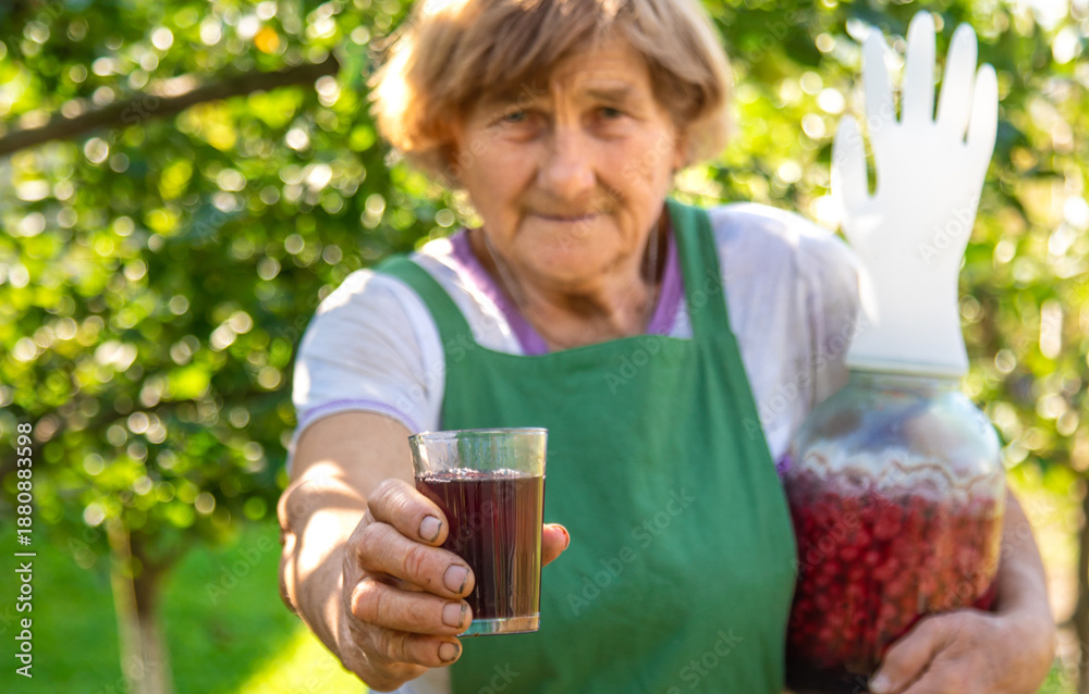 Fototapeta premium Grandma makes wine from raspberries in the garden. Selective focus.