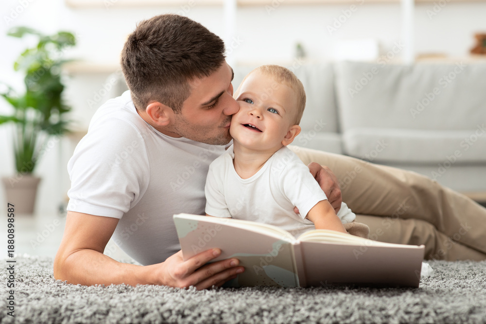 Fototapeta premium Child Care. Loving Young Father Reading Book And Kissing His Cute Toddler Son While Relaxing At Home Together, Millennial Dad Spending Time With Infant Baby, Enjoying Paternity Leave, Closeup
