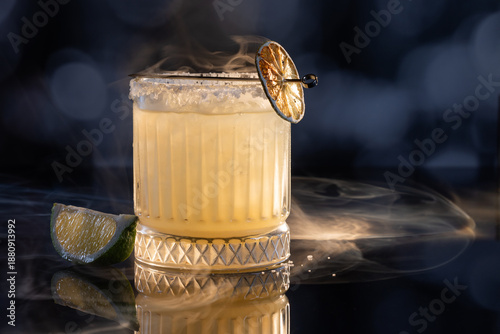 Fotografie Refreshing smokey margarita with salt on the rim served on ice garnished with a grilled lime wheel