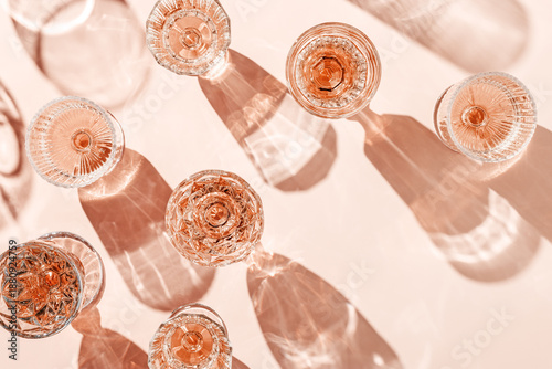 Canvas Print Minimal composition Top view glasses of rose wine or champagne on pink background, artistic shadows and sun flare