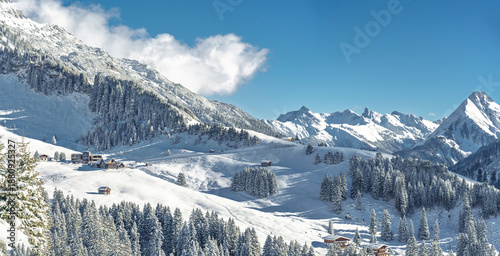 Sunny winter landscape at Lechleiten near Warth Arlberg Austria with alpine chalets hotels at the foot of Biberkopf snow-covered mountains powder slopes and panoramic alpine scenery