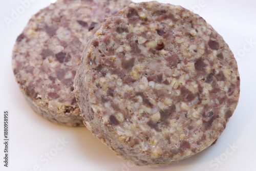 Two slices of uncooked Scottish haggis on white plate