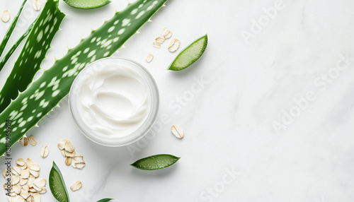White jar of cream rests among green leaves and small particles on a clean white surface. Natural ingredients and skin care product