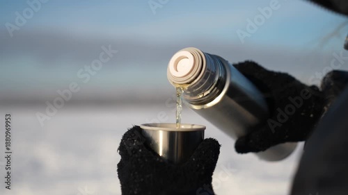 Close-up of pouring tea from a thermos in cold winter weather