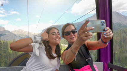 Smiling mom and daughter selfie on a gondola surrounded by beautiful views