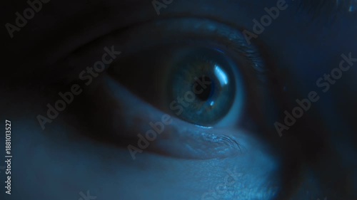 Macro view of a nervous human eye looking at display, illuminated by blue smartphone screen light, representing anxiety, social media addiction, and late-night doom scrolling.