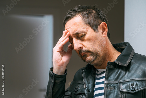 Canvas-taulu Confused adult male in leather jacket tapping his forehead, searching his memory in a moment of recall effort