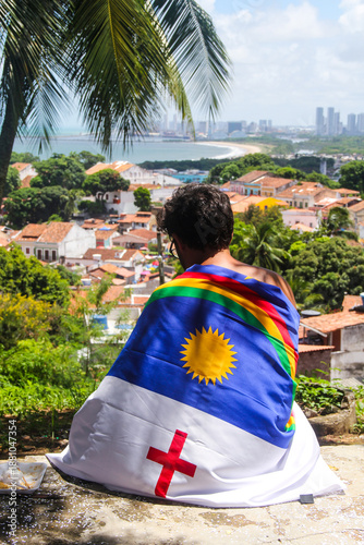 Man with Pernambuco flag looking at the Recife skyline in Olinda