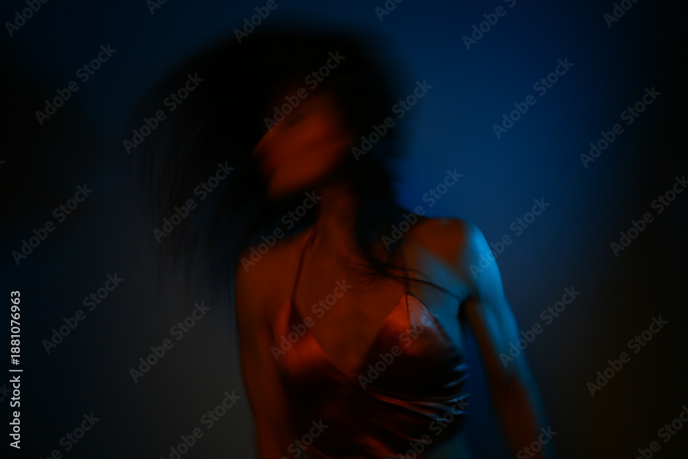 Obraz premium Young dancing woman with long hair in the dark studio iridescent colorful artistic light glows in fantasy club neon creative rays. Magic blending light, color, fantasy with sexy body girl. Art blurred