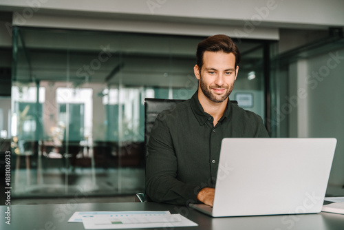 Fotografija Young professional it specialist European business man working on laptop pc sitting at desk in modern office