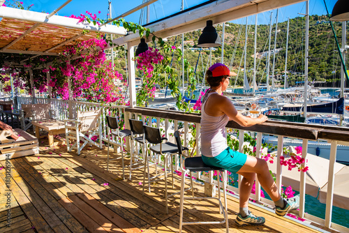 Obraz na plátně Young female tourist sitting in bar decorated with colorful flowers in Sivota po