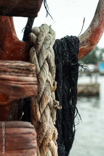 Φωτογραφία Weathered boat ropes tied to a wooden cleat at a harbor, close-up maritime detai