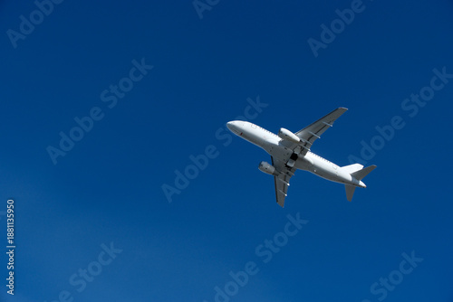 White commercial airplane climbing in clear blue sky after takeoff. White plane climbing after takeoff against the blue sky