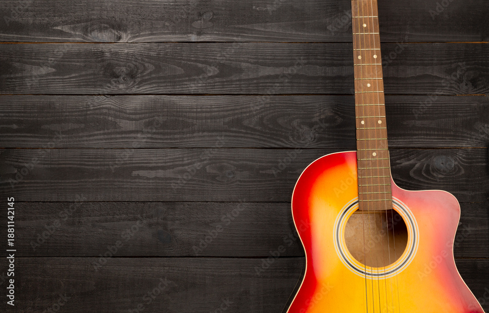 Obraz premium Bright acoustic guitar on wooden background, top view