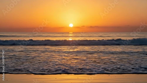 Beautiful golden sunrise over the ocean with gentle waves lapping the shore.