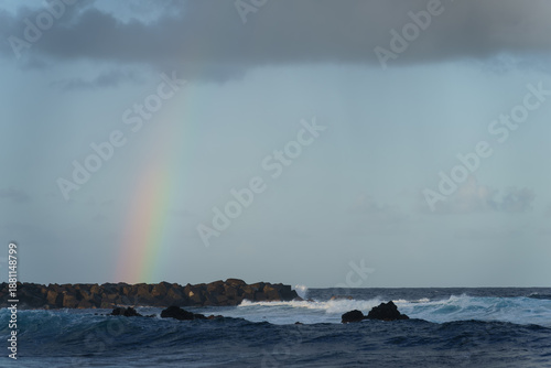 Breathtaking Coastal Scene of Tenerife with a Colorful Rainbow Over the Ocean and Rocky Jetty