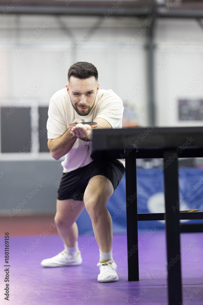 Fototapeta premium Male athlete winking holding table tennis paddle and ball