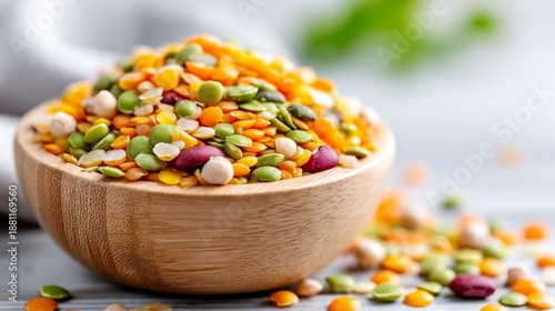 A wooden bowl filled with colorful assorted lentils and legumes on a light background